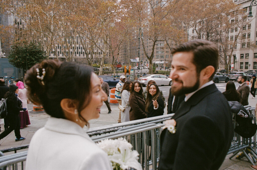 photo of bride and groom waiting outside with their guests for their new york city hall wedding, stef reyes photo